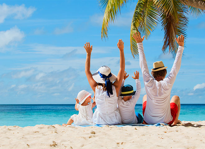 Family sitting on the beach under a palm tree