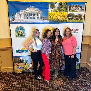 Four women smiling in front of banner