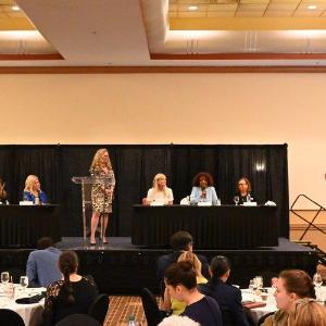 Member of a panel speaking at a table on a stage