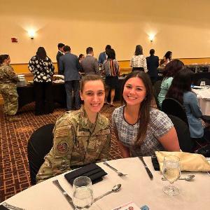 Two women smiling at table, one of whom is a military service-member