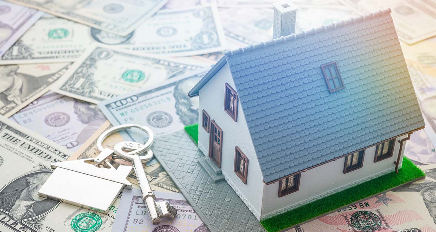 House model and home key on pile of money background