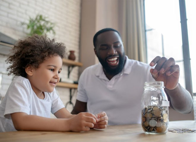 Father and child adding coins to a jar
