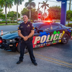Sweetwater police officer in front of car decorated with puzzle pieces