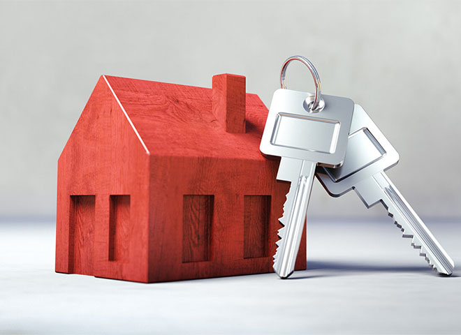 Wooden house model with silver keys leaning on it